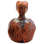 Década de 40 - Perfumeiro de vidro artístico, com influência veneziana. Apresenta um formato oval facetado e lapidado com um padrão dinâmico de espirais e linhas fluidas nas cores laranja vibrante, preto e branco imersas no vidro. Peça de coleção. Tampa colada. 15 cm.
