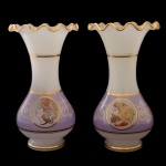 Par de vasos em opalina de formato balaústre, ornamentados à meia altura por larga faixa lilás, com filetes em ouro. Bojos abaulados, encimados por gargalos revirados e com babados. Bases circulares, retraídas e aneladas. 25 x 14 cm.