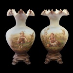 BACCARAT. France - Raro e belo par de vasos franceses em opalina leitosa, de formato piriforme, ornados por largas bordas reviradas e onduladas. Bojos abaulados, ornamentados por delicadas cenas campestres realçadas por casal de crianças. Bases em bronze lavrado, adornadas por frisos de godrões, sustentadas por pés em volutas rematados por folhagens. 38 x 22 cm.