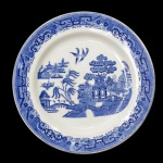 Travessa circular em louça inglesa no padrão Blue Willow. Apresenta decoração em esmalte de tom azul cobalto sobre fundo branco no padrão conhecido como Pombinhos. Marca da manufatura no verso. 28 cm.