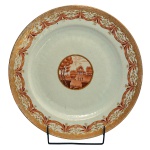 RARISSIMO - RAINHA, D. CARLOTA JOAQUINA - Medalhão em porcelana chinesa, Companhia das Índias, pertencente ao Serviço conhecido como sendo da Rainha, D. Carlota Joaquina. Formato circular e liso tendo reserva central com paisagem na cor rouge de fer. Peças deste serviço reproduzidos a página 103 do livro Louça da Aristocracia no Brasil. 34 cm. Coleção Ari Bragança de Bourbon. Participou da exposição de Porcelana Companhia das Índias no Museu Quinta das Cruzes em Funchal, 1960.