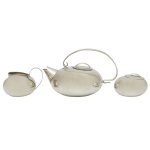 WOLFF - Conjunto para chá em metal espessurado a prata. Apresenta design Mid Century Modernista com formas esféricas suaves e funcionais, típicas do estilo modernista e e superfícies polidas espelhadas. Constando de 3 peças, sendo: bule de chá com alça curva superior (10 x 18 cm), cremeira (6 x 10 cm) e açucareiro (4 x 8 cm). Acervo Particular Maria Anna do Valle Pereira, SP.