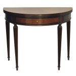 Mesa console meia-lua reversível para mesa de jogos. em madeira nobre (mogno). Tampo com borda clara e gaveta central. Pernas cilíndricas frisadas. 77 x 45 x 90 cm (fechada). 77 x 90 x 90 cm (aberta). Acervo Particular MAVP.