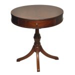 Mesa de apoio estilo tambor (drum table) em madeira mogno. Tampo circular com revestimento em couro e gaveta central. Base sustentada por uma coluna central em tripé. Puxador em madeira. 70 x 65 cm. Acervo Particular MAVP.