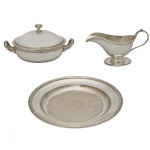 Conjunto de peças para servir em metal espessurado a prata constando de: 1 molheira (9 x 18 x 9 cm), 1 prato circular (25 cm) e 1 legumeira (8 x 18 cm). Marcas das manufaturas Fracalanza e Hutschenreuter. Acervo Particular Maria Anna do Valle Pereira, SP.