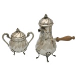 Conjunto de 2 peças em prata repuxada e cinzelada, moldadas e ornadas por gomos torcidos. Apresentam tampas abobadadas com pegas em botão floral e pés recurvos. Constando de um bule piriforme para café, com bico reto recamado por cabeça de animal e pega lateral em madeira. Acompanha açucareiro bojudo, ladeado por alças em argola. Contraste do teor de 835 mls no bule e marca de prateiro, no açucareiro marca da prata italiana de Milão com teor de 800 mls. Bule (27 x 21 cm / 788 gramas) e açucareiro (16 x 18 cm / 540 gramas). Acervo Particular MAVP.