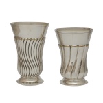 Lote constando de 2 antigos copos decorativo em metal espessurado a prata, caracterizado pelo seu design de corpo com gomos canelados e torcidos em espiral. Manufaturas Sterling e Majedi. Esse tipo de peça clássica costuma ser utilizada como floreiro de mesa ou como elemento ornamental em decorações sofisticadas. 16 x 10 cm / 14 x 10 cm. Acervo Particular Maria Anna do Valle Pereira, SP.