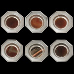 Conjunto de 6 cinzeiros de mesa octogonais em metal prateado com fundo em ágata. Apresenta modelo clássico com formato oitavado e centro circular rebaixado. 9 cm. Acervo Particular Maria Anna do Valle Pereira, SP.