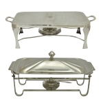 Conjunto de 2 rechaud  de formato retangular em metal prateado de modelo clássico. Composto por uma base com alças, suporte para fogareiro a álcool e outro com uma tampa superior piramidal com puxador. 23 x 45 x 25 cm e 14 x 48 x 24 cm. Acervo Particular Maria Anna do Valle Pereira, SP.