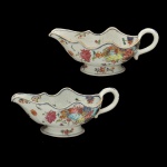 CHINA MODERNA - Par de molheiras de formato navicular em porcelana no estilo da Companhia das Índias. Decoração policromada com buquês de flores. Formato característico com borda sinuosa, bico alongado e uma alça curva. 9 x 23 x 11 cm.