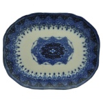 COPELAND. England. Séc. XIX - Travessa em porcelana inglesa, caracterizada pelo estilo "azul borrão" (flow blue). Apresenta formato retangular com cantos arredondados, um medalhão central detalhado cercado por uma borda geométrica e floral em tom azul-cobalto intenso. Marca da manufatura no verso. 4 x 43 x 33 cm.