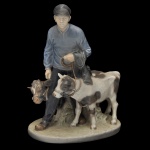 ROYAL COPENHAGEN. Artista Christian Thomsen  Menino com dois Bezerros. Estatueta em porcelana dinamarquesa exibindo um acabamento vidrado em tons pastel e suaves, típicos da marca (azul-cinzento, branco e marrom). No verso marca da manufatura e o número do modelo #1858. 23 x 18 x 11 cm.