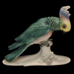 HERTWIG & CO. (Katzhütte, Alemanha) - Estatueta em porcelana (faiança) alemã policromada e esmaltada retratando uma ave tropical com tons verdes estruturais marcantes, peito rosado e uma crista proeminente em degrade multicolorido. Ela repousa sobre uma base decorada com folhas e um fruto em relevo. No verso marca da manufatura. utilizada entre 1941 e 1958. 34 x 42 x 13 cm.