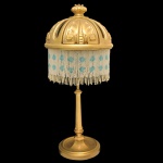 Original luminária de mesa, com coluna facetada em bronze dourado. Cúpula semiesférica ornada por estilizações e vazados, bordada por finos colares perolados brancos realçados por medalhões de cor azul. Base circular realçada por raízes. 50 x 23 cm.