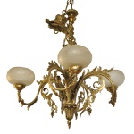Lustre em bronze dourado, estilo Rocaille, para 4 luzes. Base no formato de sino, encimada por braços recurvos e recamados por profusas folhagens, rematados nas extremidades por globos achatados em cristal francês Baccarat, acetinado. Parte superior com coluna lavrada realçada por adornos e canopla no topo. 126 x 80 cm.