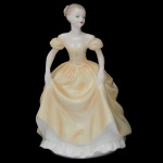 Ladies Of Fashion. Bone China. "Emily" - Rara estatueta inglesa em porcelana representando Dama segurando vestido amarelo. 20 x 14 cm.
