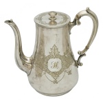 Elegante bule em metal espessurado a prata apresentando formato afunilado. Ornamentação gravada em estilo guilhoché e um medalhão central com o monograma da letra "H" em estilo caligráfico. Marcado por curvas sinuosas no cabo e no bico. 22 x 18 x 11 cm.