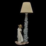 LLADRÓ BY NAO 1109. Titulada So Shy  Tão Tímida de 1989 - Luminária espanhola em porcelana brilhante e policromada. Sob a base marca da manufatura. 38 x 22 x 14 cm.