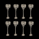 Conjunto de oito marcadores de lugares de mesa em metal prateado apresentando um design ornamentado de uvas e folhas e base em formato de cesta. 11 cm.