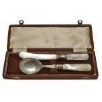Elegante conjunto de talheres (colher e faca). Apresenta lâminas em metal inglês Old Sheffield (E.P.N.S.) com cabos genuínos de madrepérola acomodados em um estojo original revestido de veludo. Marca do fabricante B&S e a especificação do banho EP (Electro Plated).