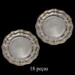 Conjunto com 18 pratos em metal prateado. Bordas recortadas com movimentos e frisos em alto relevo.18 cm.