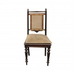Cadeira em madeira nobre escura com pés torneados e encosto estofado com detalhes em relevo. Painel central retangular estofado, emoldurado por travessas de madeira. Parte superior com pinos ou torneadas. Pernas dianteiras com detalhado trabalho de tornearia com relevos circulares e frisos.