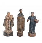 Séc. XIX - Conjunto de três pequenas esculturas do imaginário da arte sacra popular brasileira, em madeira entalhada com vestígios de policromia. A) Representação de Santo Antônio com  Jesus nos braços. Apresenta resquícios de policromia. B) Representação de Santo Antônio de túnica longa e capa, com entalhe rústico e base cilíndrica. Apresenta resquícios de policromia. C) Representação de Santo Antônio com hábito escuro segurando um livro nos braços (característica comum em imagens de Santo Antônio ou São Benedito). Apresenta resquícios de policromia e algumas perdas. 9 x 4 cm / 10 x 3 cm / 9 x 5 cm. Desgastes naturais, rachaduras na madeira e perdas na camada pictórica (policromia) são normais em peças de época,