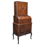 Cômoda papeleira em madeira nobre, estilo inglês, construída com 3 módulos superpostos de formato retangular. Exibe elegante decoração com gomos, florões e frisos estilizados. Apresenta Cabinet, armário de 2 portas ricamente almofadadas, com prateleira interna, encimado por escrivaninha com frente chanfrada e parte interna com escaninhos e gavetinha. Parte superior com alçada acompanhando o estilo e frontão plano. Base reta com pernas curvilíneas rematadas por pés revirados. 162 x 76 x 46