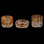 Conjunto para toucador em cristal prensado com a técnica overlay, que sobrepõe camadas coloridas e incolores. Apresenta arcos e motivos de diamante em relevo na base incolor, com a parte superior realçada por um tom âmbar vibrante. Composto por 3 peças, sendo 1 pote com tampa (7 x 8 cm), 1 pote sem tampa (6 x 8 cm) e um bowl (2 x 11 cm).
