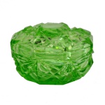 Caixa para joias em vidro na cor verde vibrante e propriedades fluorescentes sob luz. Apresenta formato circular com lapidações geométricas. 5  x 10 cm.