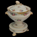 Pequeno potiche para Pot pourri, de formato balaústre, em porcelana branca ornamentado por adornos florais e filetes dourados. Bojo cônico, ladeado por alças reviradas. Base esparramada sobre peanha saliente e circular, sustentada por pés recortados. Tampa abobadada com pega no formato de pinha. Apresenta restauro. 18 x 16 cm.