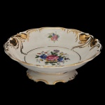 Centro de mesa em porcelana  branca da manufatura nacional Real, São Paulo. Apresenta formato ondulado com bordas recortadas, realces decorativos em ouro e ramalhetes florais. Prato fundo com borda ondulada, apoiada em base esparramada e recortada por volutas. Marca da manufatura na base. 6 x 20 cm.