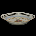 BAVÁRIA - Covilhete em porcelana alemã de formato oblongo. Borda com galeria vazada e decoração floral no centro com detalhes dourados. Marca da manufatura na base. 5 x 22 x 14 cm.