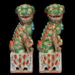 Par de Cães de Fó, idênticos e com filhotes ao lado, em porcelana chinesa policromada. Apresentam-se sentados, com bocas abertas e dentes à mostra. Bases quadrangulares, vazadas e ornadas por estilizações e adornos geométricos. Marcas de fabricação do séc. XX sob as bases. 21 x 7 x 6 cm.