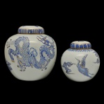 Conjunto de dois potiches globulares de tamanhos distintos, decoradas em azul e dourado. O maior, apresentando dragão voando, e o outro com fênix no meio das nuvens. Tampas levemente abobadadas, realçadas por frisos geométricos. Um deles assinado e datado Sonia (19)88. 20 x 20 cm e 16 x 14 cm. Um deles assinado e datado Sonia (19)88.