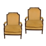 Par de poltronas estilo inglês, em madeira nobre realçada por discretos frisos canelados. Encostos retos com quinas recortadas, ladeados por braços com suportes recurvos. Assentos realçados por almofadas altas. Saias retilíneas, apoiadas em pernas retas com anelados quadrangulares nas bases. Estofamento em tecido amarelo mostarda. 92 x 65 x 50 cm.