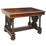 Mesa em madeira nobre, lavrada e esculpida em estilo manuelino. Tampo retangular com larga borda estilizada, apoiado em saia lisa. Colunas laterais espiraladas, centralizando montantes recortados e ornados por volutas e estilizações, apoiadas em suportes retos com larga trave central formando amarração em H. Pés no formato de bolotas. 74 x 115 x 66 cm.