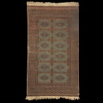 Tapete oriental feito de lã tecida à mão,  medindo 154 x 88 cm. Desgastes nas laterais. Sinais de uso e do tempo. Apresenta um padrão tradicional de medalhões geométricos centrais típico de tapeçarias tribais como as das regiões Baluch ou Turkmen, com tons terrosos, verdes e franjas nas extremidades.