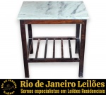 MESA LATERAL EXECUTADA EM MADEIRA NOBRE ESCURA, APRESENTANDO TAMPO EM MÁRMORE. COMPÕE-SE DE QUATRO PERNAS DE SEÇÃO QUADRADA UNIDAS POR PRATELEIRA INFERIOR EM RIPAS DE MADEIRA VAZADAS, MEDINDO 50 X 50 X 40 CM. APRESENTA MARCAS DO TEMPO, USO, DESGASTES, LEVES MANCHAS NATURAIS NO MÁRMORE E/OU PEQUENAS IMPERFEIÇÕES COMPATÍVEIS COM SUA UTILIZAÇÃO E ESTADO DE CONSERVAÇÃO, CONFORME FOTOS EXTRAS. ESTE LOTE ESTARÁ DISPONÍVEL PARA RETIRADA NO BAIRRO COPACABANA, RIO DE JANEIRO/RJ, SOMENTE NAS DATAS XXXXXXXX, MEDIANTE AGENDAMENTO PRÉVIO. A NÃO RETIRADA DO LOTE NAS DATAS ESTABELECIDAS IMPLICARÁ NO CANCELAMENTO DA ARREMATAÇÃO, COM INCIDÊNCIA DE MULTA CORRESPONDENTE A 50% DO VALOR DO ARREMATE, NOS TERMOS DO EDITAL E CONDIÇÕES DO LEILÃO. ESTE LOTE DEVERÁ SER RETIRADO E/OU TRANSPORTADO EXCLUSIVAMENTE POR EMPRESA TRANSPORTADORA, FICANDO SOB TOTAL RESPONSABILIDADE DO ARREMATANTE A CONTRATAÇÃO, CUSTOS, AGENDAMENTO E ACOMPANHAMENTO DA RETIRADA. A GALERIA NÃO REALIZA EMBALAGEM, DESMONTAGEM, CARREGAMENTO OU ENTREGA DO REFERIDO LOTE. ESCLAREÇA TODAS AS DÚVIDAS ANTES DE EFETUAR SEU LANCE, QUE SERÁ CONSIDERADO IRREVOGÁVEL E IRRETRATÁVEL. CONSULTE PREVIAMENTE OS TERMOS E CONDIÇÕES DISPONÍVEIS NO SITE. CONTATO (21) 98264-3000.