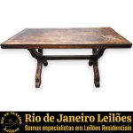 MESA DE JANTAR, ESTILO COLONIAL COM INFLUÊNCIA MEDIEVAL, EXECUTADA EM MADEIRA NOBRE ESCURA, APRESENTA ROBUSTO TAMPO COM MOLDURA EM ENTALHE REBAIXADO E ESTRUTURA DE SUSTENTAÇÃO COMPOSTA POR DOIS CAVALETES LATERAIS EM FORMATO DE LIRA, UNIDOS POR TRAVESSA CENTRAL RETA DE REFORÇO, MEDINDO 76 X 160 X 80 CM. APRESENTA MARCAS DO TEMPO, USO, RISCOS SUPERFICIAIS, ARRANHÕES, DESGASTES ACENTUADOS NO VERNIZ/PÁTINA, MANCHAS ESBRANQUIÇADAS E DE UMIDADE NO TAMPO E/OU PEQUENAS IMPERFEIÇÕES COMPATÍVEIS COM SUA UTILIZAÇÃO E ESTADO DE CONSERVAÇÃO, CONFORME FOTOS EXTRAS. ESTE LOTE ESTARÁ DISPONÍVEL PARA RETIRADA NO BAIRRO COPACABANA, RIO DE JANEIRO/RJ, SOMENTE NAS DATAS XXXXXXXX, MEDIANTE AGENDAMENTO PRÉVIO. A NÃO RETIRADA DO LOTE NAS DATAS ESTABELECIDAS IMPLICARÁ NO CANCELAMENTO DA ARREMATAÇÃO, COM INCIDÊNCIA DE MULTA CORRESPONDENTE A 50% DO VALOR DO ARREMATE, NOS TERMOS DO EDITAL E CONDIÇÕES DO LEILÃO. ESTE LOTE DEVERÁ SER RETIRADO E/OU TRANSPORTADO EXCLUSIVAMENTE POR EMPRESA TRANSPORTADORA, FICANDO SOB TOTAL RESPONSABILIDADE DO ARREMATANTE A CONTRATAÇÃO, CUSTOS, AGENDAMENTO E ACOMPANHAMENTO DA RETIRADA. A GALERIA NÃO REALIZA EMBALAGEM, DESMONTAGEM, CARREGAMENTO OU ENTREGA DO REFERIDO LOTE. ESCLAREÇA TODAS AS DÚVIDAS ANTES DE EFETUAR SEU LANCE, QUE SERÁ CONSIDERADO IRREVOGÁVEL E IRRETRATÁVEL. CONSULTE PREVIAMENTE OS TERMOS E CONDIÇÕES DISPONÍVEIS NO SITE. CONTATO (21) 98264-3000. ESTE LOTE COMBINA COM OS LOTES Nº 21, 187 E 375.