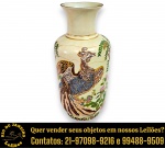 VASO, ESTILO SATSUMA, EXECUTADO EM PORCELANA ESMALTADA E VITRIFICADA, APRESENTANDO CORPO CILÍNDRICO COM PESCOÇO ALARGADO E BOCA ALARGADA, BORDAS FILETADAS EM VIBRANTE DOURADO E DECORAÇÃO POLICROMADA, PINTADA À MÃO, REPRESENTANDO AVE FANTÁSTICA ENTRE FLORES E FOLHAGENS, MEDINDO 36 X 16 CM. APRESENTA MARCAS DO TEMPO, USO, DESGASTES E/OU IMPERFEIÇÕES COMPATÍVEIS COM SUA UTILIZAÇÃO E ESTADO DE CONSERVAÇÃO, CONFORME FOTOS EXTRAS. ESCLAREÇA TODAS AS DÚVIDAS ANTES DE EFETUAR SEU LANCE, QUE SERÁ CONSIDERADO IRREVOGÁVEL E IRRETRATÁVEL. CONSULTE PREVIAMENTE OS TERMOS E CONDIÇÕES DISPONÍVEIS NO SITE. CONTATO VIA TELEFONE OU WHATSAPP: (21) 98264-3000.