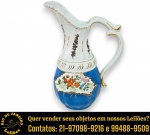 JARRA EXECUTADA EM PORCELANA ESMALTADA E VITRIFICADA, PINTADO À MÃO, APRESENTANDO CORPO BOJUDO E BOMBEADO COM MEDALHÕES RESERVADOS COM MOTIVOS FLORAIS EM DELICADA POLICROMIA, PESCOÇO LONGO, BICO CURVO E ALÇA CURVA EM VOLUTAS COM DETALHES DECORATIVOS, MEDINDO 30 X 21 X 13 CM. APRESENTA MARCAS DO TEMPO, USO, DESGASTES E/OU IMPERFEIÇÕES COMPATÍVEIS COM SUA UTILIZAÇÃO E ESTADO DE CONSERVAÇÃO, CONFORME FOTOS EXTRAS. ESCLAREÇA TODAS AS DÚVIDAS ANTES DE EFETUAR SEU LANCE, QUE SERÁ CONSIDERADO IRREVOGÁVEL E IRRETRATÁVEL. CONSULTE PREVIAMENTE OS TERMOS E CONDIÇÕES DISPONÍVEIS NO SITE. CONTATO VIA TELEFONE OU WHATSAPP: (21) 98264-3000.