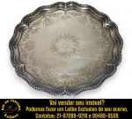 SALVA EXECUTADA EM METAL, ESPESSURADO À PRATA, FORMATO RECORTADO E BORDA LOBADA E ONDULADA ORNAMENTADA POR DELICADO FRISO PEROLADO, CENTRO LIGEIRAMENTE REBAIXADO, APRESENTANDO REFINADA GRAVAÇÃO MANUAL EM MOTIVOS FLORAIS E FOLHAGENS, MONOGRAMA CENTRAL EM LETRAS CURSIVAS, APOIADA SOBRE TRÊS PÉS ORNAMENTAIS, MEDINDO 4 X 29,5 CM. APRESENTAM MARCAS DO TEMPO, USO, DESGASTES E/OU IMPERFEIÇÕES COMPATÍVEIS COM SUA UTILIZAÇÃO E ESTADO DE CONSERVAÇÃO, CONFORME FOTOS EXTRAS. ESCLAREÇA TODAS AS DÚVIDAS ANTES DE EFETUAR SEU LANCE, QUE SERÁ CONSIDERADO IRREVOGÁVEL E IRRETRATÁVEL. CONSULTE PREVIAMENTE OS TERMOS E CONDIÇÕES DISPONÍVEIS NO SITE. CONTATO VIA TELEFONE OU WHATSAPP: (21) 98264-3000. 