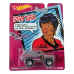Hot Wheels Mattel  1988 Jeep Wagoneer  miniatura colecionável em escala 1/64 da série Pop Culture Star Trek, edição 2014, dedicada à personagem Lt. Uhura. Carroceria em acabamento rosa/lilás metalizado com teto prateado e decoração temática de Star Trek e Lt. Uhura. Construção Metal/Metal, com carroceria e chassi em metal, e rodas Real Riders com pneus de borracha. Código BDT15. Fabricada na Tailândia. Miniatura lacrada em sua embalagem original, apresentando sinais de armazenamento na cartela conforme fotos. Produto exatamente das fotos do anúncio.