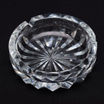STRAUSS - Cinzeiro em cristal translúcido, com lapidação radial na base. Altura e diâmetro: 4 x 12cm.