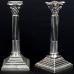 Excepcional par de grandes castiçais ingleses, circa 1900, estilo Georgiano em prata cinzelada, em forma de coluna coríntia com bobeches destacáveis, hastes gomadas, contrastes de origem, leão rampante, cidade de Londres, letra data e ano 1907 e punção do prateiro. Altura: 31cm. Peso bruto: 1.8Kg. Apresenta marcas de uso.