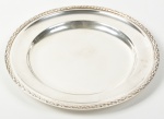 WOLFF - Travessa redonda em metal espessurado a prata, bordas cinzeladas em escamas. Diâmetro: 29,5cm.