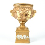 Cachepot em terracota grega com aplicação de pátina dourada, decorada com anjos e feras. Altura e diâmetro: 22cm.