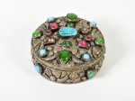 Antiga caixa em prata, ricamente decorada com pedrarias, cinzeladas com escaravelhos, pequenos motivos florais e faraós. Altura e diâmetro: 5 x 9cm.