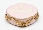 AVEIRO - Porta joias em porcelana portuguesa esmaltada e vitrificada na cor rosa, com aplicação floral dourada em alto relevo (apresenta bicados). Tampa com imagens de anjos em alto relevo. Medidas: 4,5 x 11 x 10cm.